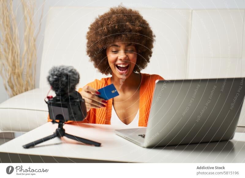 junge lateinamerikanische Frau mit Afro-Haar, die mit ihrem Laptop online einkauft und mit Kreditkarte bezahlt Afro-Look Behaarung während kaufen bezahlen Glück
