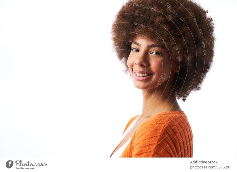 Porträt einer lächelnden Latina-Frau mit Afro-Haar, die in die Kamera schaut, auf weißem Hintergrund Lächeln lateinamerikanisch Afro-Look Behaarung Blick