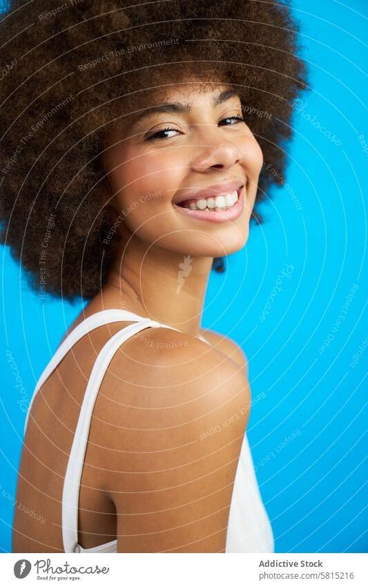 Porträt einer lateinamerikanischen Frau mit Afro-Haar lächelnd Studio-Foto mit blauem Hintergrund Afro-Look Behaarung Lächeln Atelier Model Schönheit Person