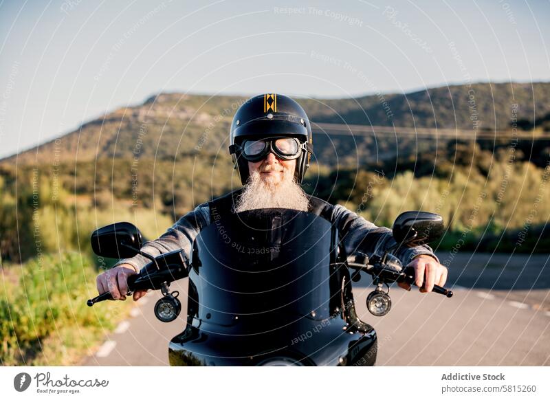 Älterer Motorradfahrer mit Bart genießt eine Fahrt Senior Mann Vollbart Schutzhelm Mitfahrgelegenheit Biker im Freien in die Kamera schauen Fahrzeug Transport