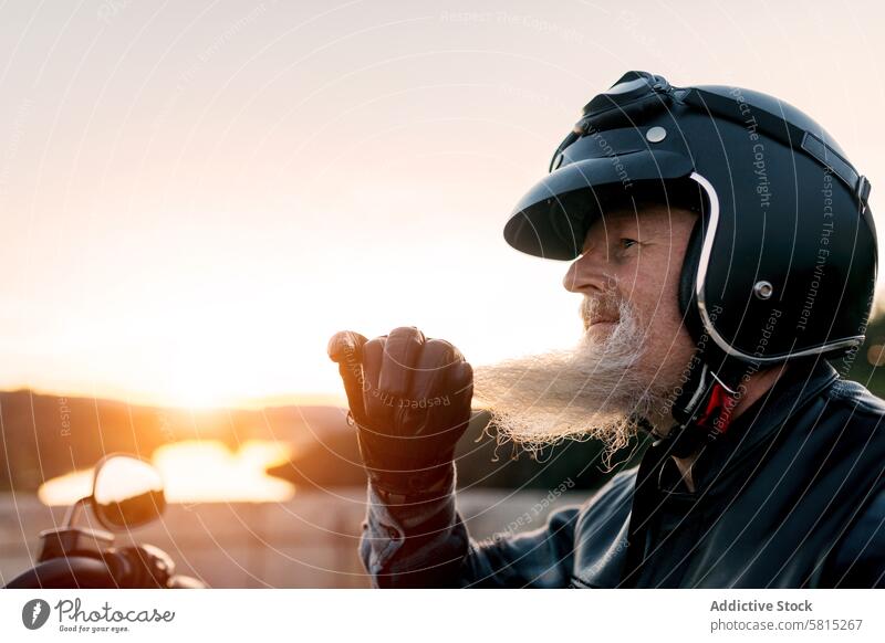 Älterer Motorradfahrer mit Helm genießt den Sonnenuntergang Senior Biker Schutzhelm Mitfahrgelegenheit männlich älter Freiheit malerisch Abenteuer Gelassenheit