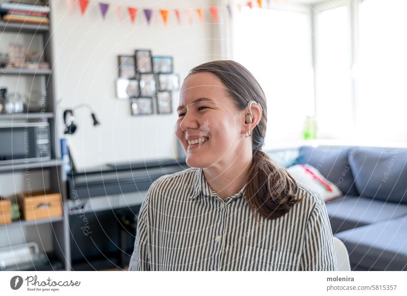 Porträt einer Frau mit Hörgerät Gehör Ohr Person taub Unterstützung Gesundheit Gerät Erwachsener Behinderung 30s weiß Lächeln Hemd heimwärts