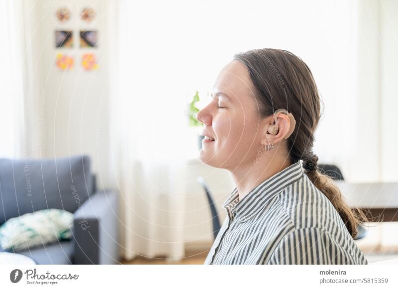 Porträt einer Frau mit Hörgerät Gehör Ohr Person taub Unterstützung Gesundheit Gerät Erwachsener Behinderung 30s weiß Lächeln Hemd heimwärts