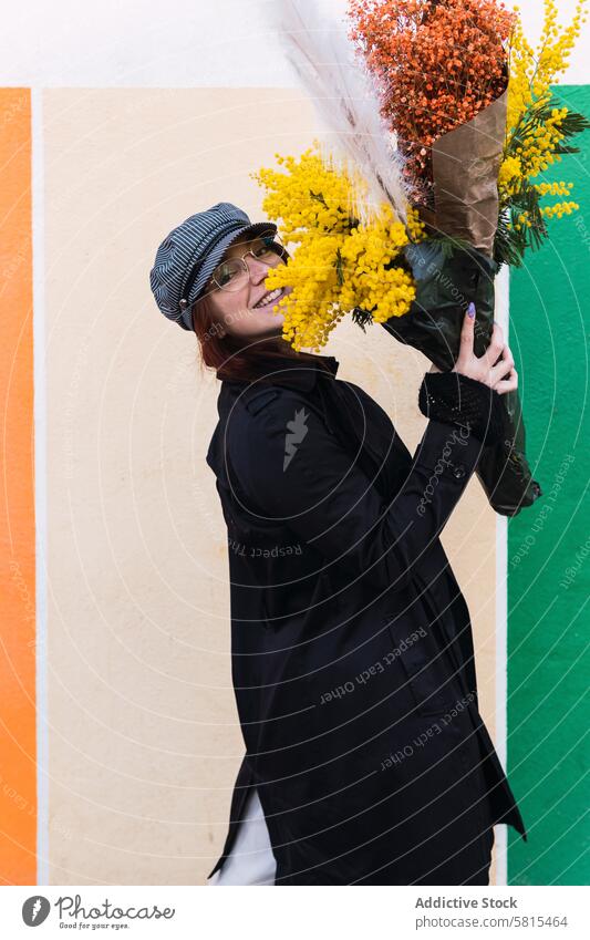 Frau mit Blumen lächelnd gegen bunte Wand Lächeln Straße Stil Glück Blumenstrauß Straßenbelag farbenfroh führen jung urban Oberbekleidung Saison Freude Haufen