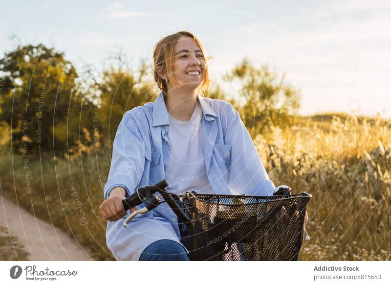 blonde junge Frau beim Radfahren auf einem Feld. Sonnenuntergang Landschaft Natur Fahrrad Glück Fahrradfahren Frühling Ausflug Straße Himmel Sommer Mädchen