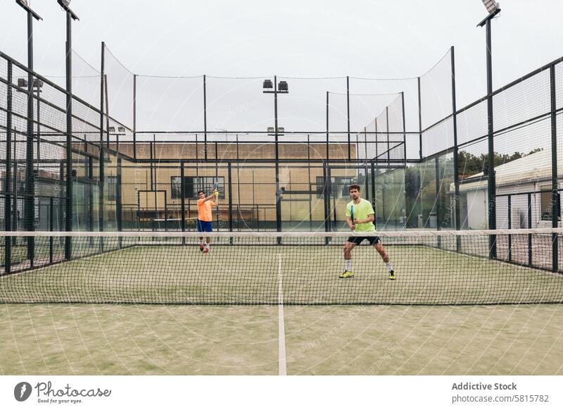 zwei junge Männer spielen Paddle-Tennis Remmidemmi Paddel Sport Erholung Erwachsener Spiel Paar Padel Gericht attraktiv Netz 20s lateinamerikanisch Mann Ball