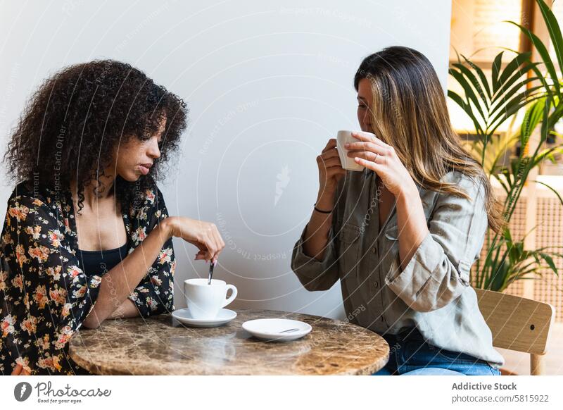 Multiethnische Freundinnen mit Kaffee in einem Cafe Heißgetränk genießen Getränk Zeit verbringen Wochenende Tisch feminin Kantine Frauen Zusammensein