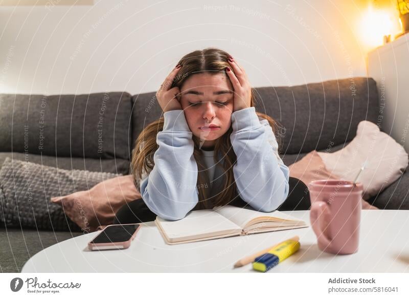 Gestresstes junges Mädchen beim Lernen zu Hause heimwärts gestresst studierend müde Buch Smartphone Tasse Frau Bildung Schüler Angst überwältigt Sitzen Liege