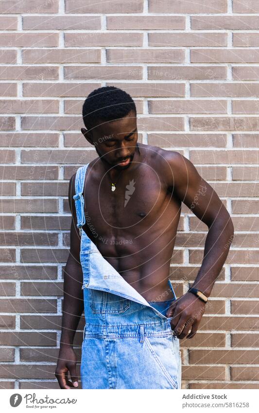 Fit schwarzer Mann in Latzhose in der Stadt gesamt nackter Torso passen Model Großstadt gutaussehend ohne Hemd muskulös Outfit männlich ethnisch Afroamerikaner