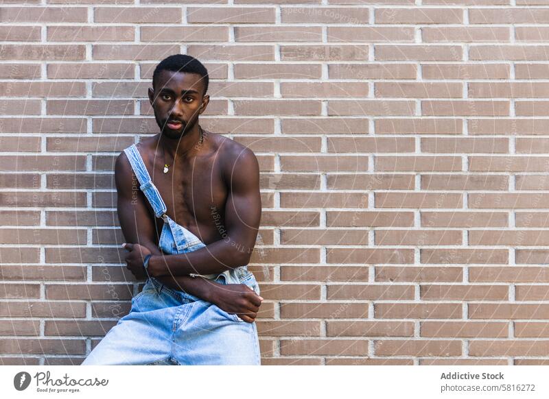 Fit schwarzer Mann in Latzhose in der Stadt gesamt nackter Torso passen Model Großstadt gutaussehend ohne Hemd muskulös Outfit männlich ethnisch Afroamerikaner