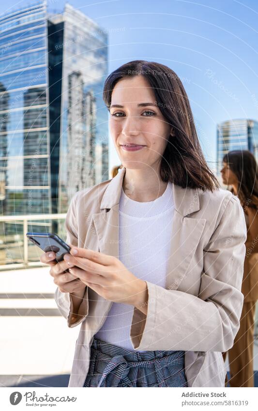 Eine Frau in Geschäftskleidung steht draußen mit einem Handy in der Hand und will es benutzen. schöne Menschen modern attraktiv Schönheit Pause. Kaffeepause