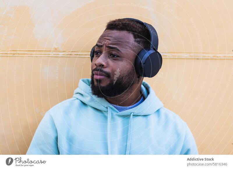 Optimistischer schwarzer Hipster, der mit Kopfhörern Musik hört Mann zuhören genießen Vollbart Drahtlos Erwachsener Afroamerikaner ethnisch männlich lässig