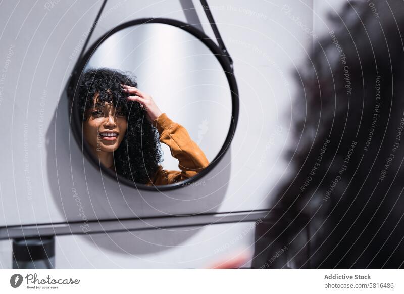 Lächelnde schwarze Frau vor dem Spiegel zu Hause Reflexion & Spiegelung wach Morgen Vorschein Schönheit Routine feminin perfekt Afroamerikaner krause Haare jung