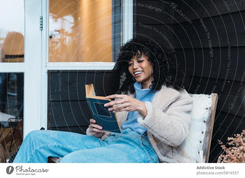 Schwarze Frau liest draußen ein Buch lesen ruhen sich[Akk] entspannen Kälte Terrasse Literatur Etage Roman Afroamerikaner schwarz zu Hause Wochenende Lächeln