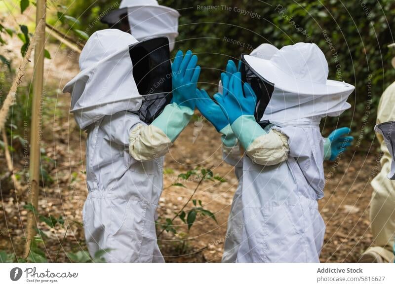Gesichtslose Gruppe von Kindern in Schutzkleidung in einem Bienenstock Tracht behüten Zusammensein Garten Landschaft Sicherheit Handschuh Gummi Bienenkorb Wiese