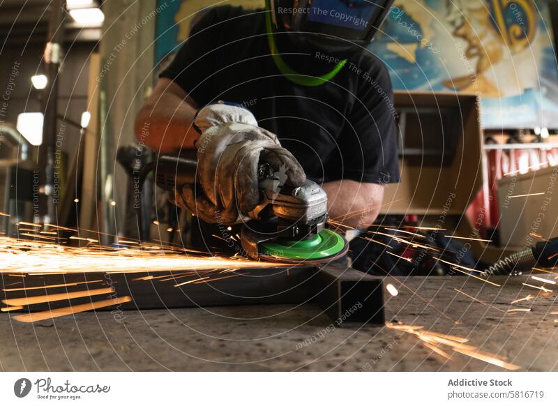 Männlicher Arbeiter mit elektrischer Schleifmaschine in der Werkstatt Maschine Mann geschnitten Schweißer Metallbearbeitung Funken männlich Detailaufnahme