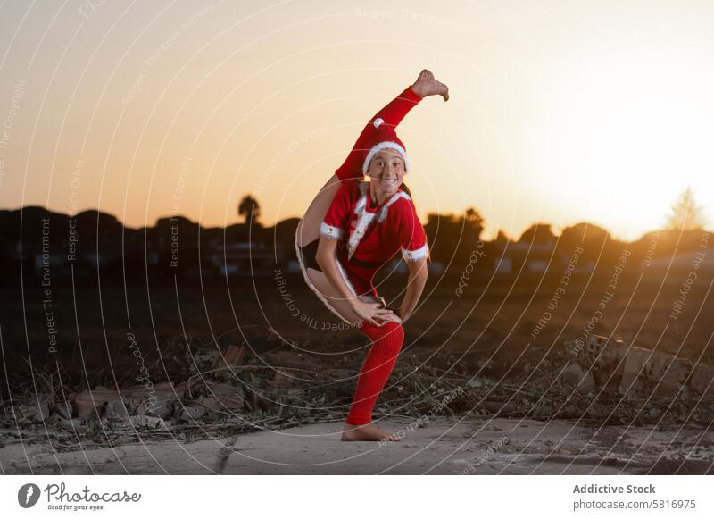 junges Mädchen, das rhythmische Gymnastikübungen macht und ein Weihnachtsmannkleid trägt Jugend disziplinieren strecken Frau Athlet Aufwärmen Gesundheit Aerobic