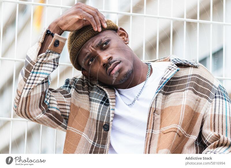 Trendiger afroamerikanischer Mann auf der Straße Großstadt fettarm Zaun Stil Outfit urban modern jung männlich schwarz ethnisch Afroamerikaner trendy lässig