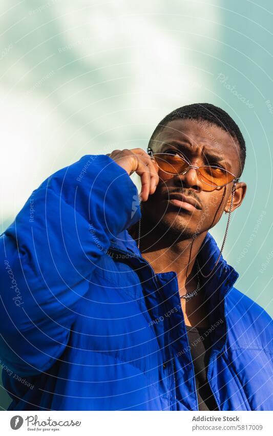 Stilvoller schwarzer Mann mit Sonnenbrille auf der Straße trendy Outfit cool urban männlich ethnisch Afroamerikaner selbstbewusst modern warm Jacke Gebäude