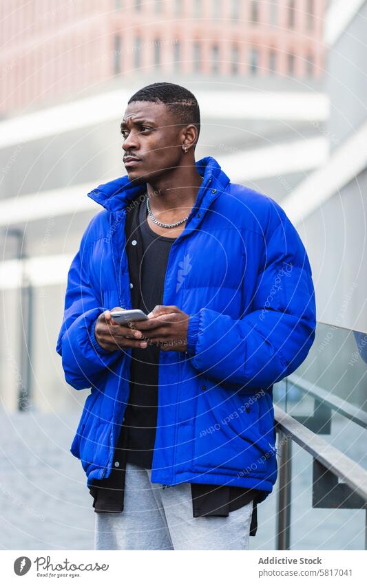 Stilvoller schwarzer Mann, der mit seinem Handy in sozialen Medien chattet Textnachricht Smartphone soziale Netzwerke Nachricht Talkrunde benutzend unterhalten