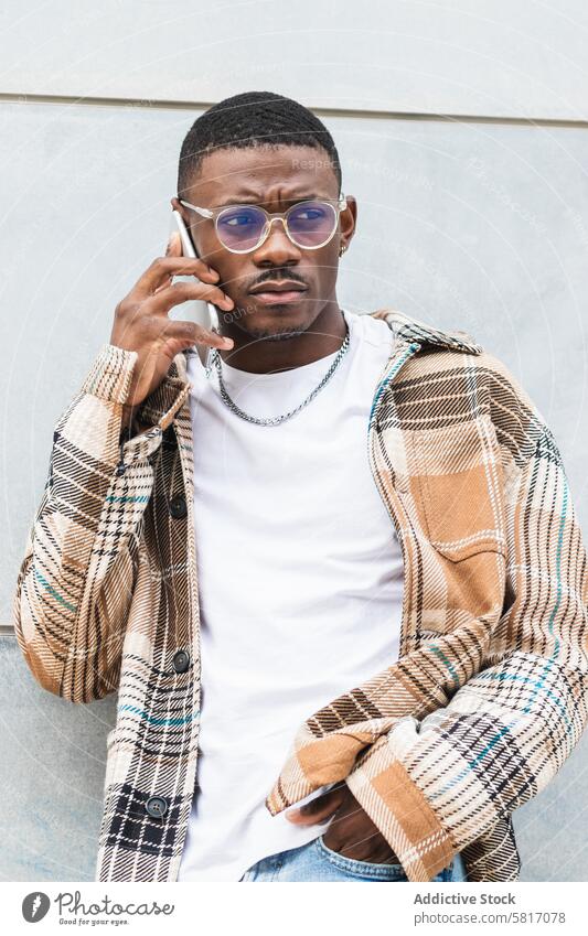 Stylish schwarz männlich mit Smartphone auf der Straße Mann reden sprechen benutzend Großstadt Wand Stil Outfit jung urban trendy ethnisch Afroamerikaner