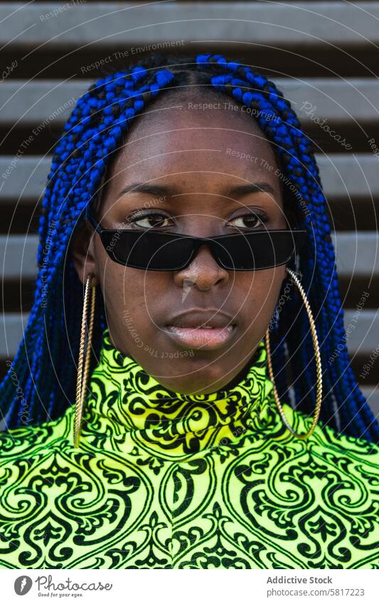 Stilvolle ethnische Frau auf Stadt Straße blaue Haare Geflecht Frisur trendy Outfit selbstbewusst cool ernst Afroamerikaner schwarz lebhaft Bestimmen Sie
