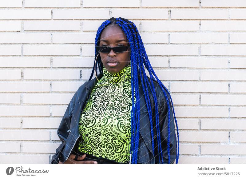 Entschlossene schwarze Frau in trendiger Kleidung in der Stadt trendy lebhaft Outfit blaue Haare Geflecht Frisur Bestimmen Sie Vorschein Stil ethnisch