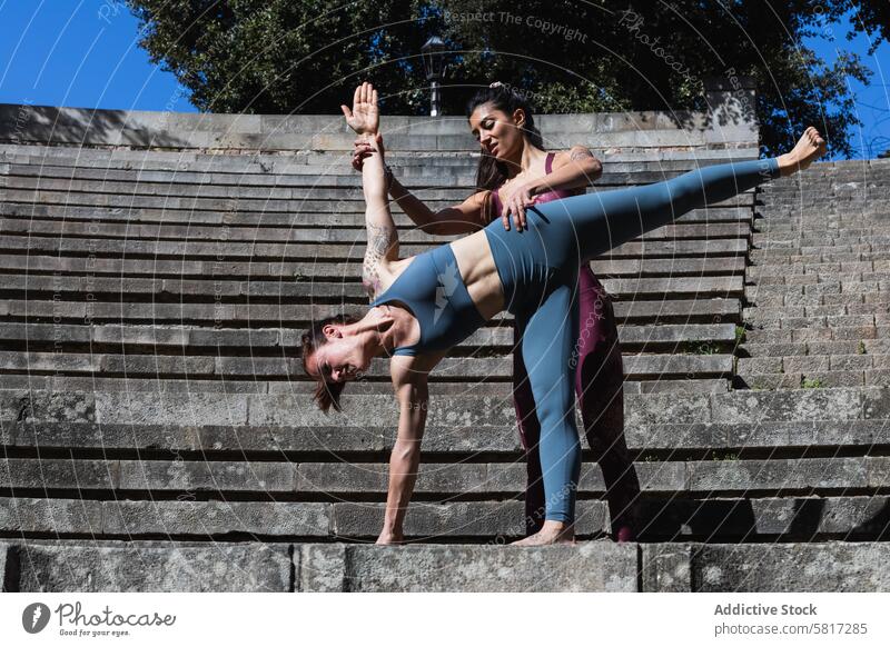 Yogalehrer hilft einer Frau bei der Halbmond-Pose Ausbilderin Hilfsbereitschaft Frauen üben abstützen beweglich Dehnung Personal Zusammensein Aktivität