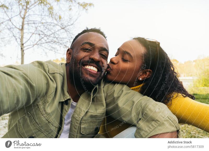 Afroamerikanisches Paar macht ein Selfie und küsst sich auf die Wange. Frau Glück Afro-Look Mann jung Afrikanisch schwarz Menschen heiter Amerikaner Porträt