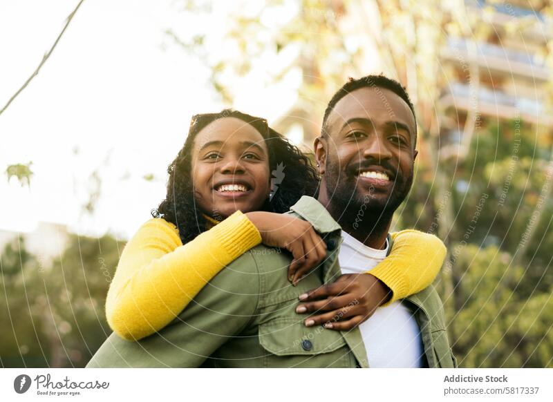 Porträt eines lächelnden schwarzen Mannes, der seine Schwester huckepack nimmt Huckepack Glück Mädchen Spaß Menschen Zusammensein tragen Frau Lächeln männlich