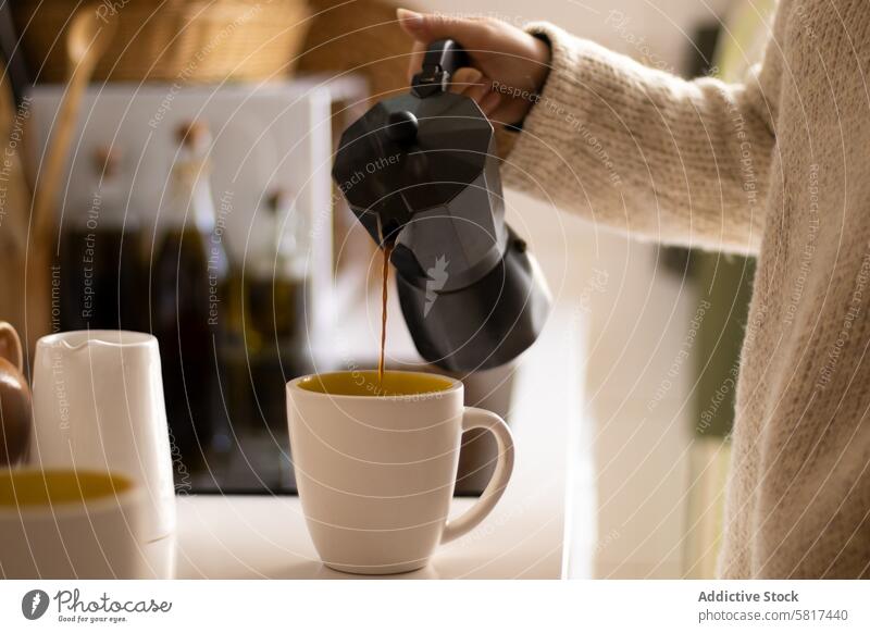 Hand einer Frau gießt Kaffee mit einer italienischen Kaffeemaschine in einer Küche Tasse trinken Getränk Café Espresso Koffein heiß eingießen Becher Frühstück