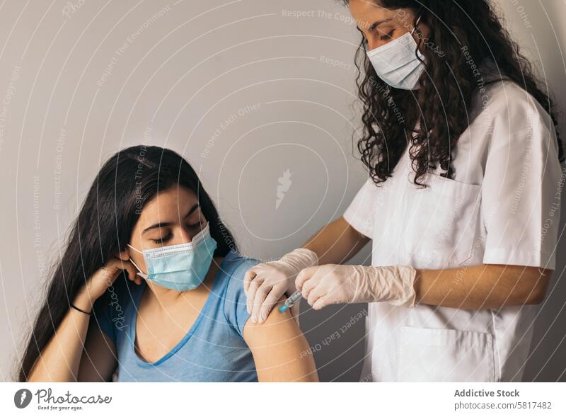 Arzt macht Impfung an junger Frau mit chirurgischer Maske geduldig medizinisch Mundschutz Einspritzung Gesundheit Medizin Klinik Coronavirus Prävention