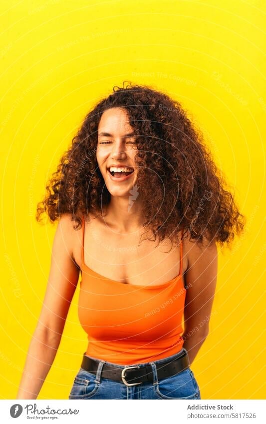 schöne afro Frau lächelnd und lachend Porträt lehnt an einer gelben Wand Afro-Look Afrikanisch schwarz jung attraktiv Amerikaner lässig heiter Schönheit Glück