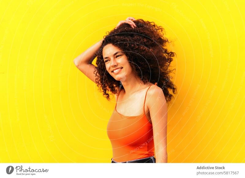 schöne afro Frau schaut zur Seite Porträt lehnt an einer gelben Wand Afro-Look Afrikanisch schwarz jung attraktiv Amerikaner lässig heiter Schönheit Glück