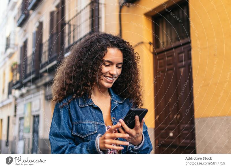 Fröhliches lateinamerikanisches Mädchen benutzt Smartphone im Freien jung Glück Park Straße Großstadt Funktelefon lässig Lächeln Lifestyle Telefon benutzend