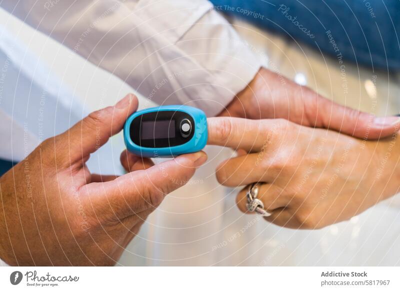 Der Arzt legt seinem Patienten ein Pulsoximeter in die Hand, um die Sauerstoffsättigung im Blut und die Herzfrequenz zu messen. Analysieren