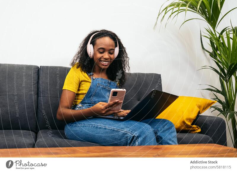 Junge schwarze Frau arbeitet mit Laptop und genießt Musik zu Hause digitaler Lebensstil Technik & Technologie Tablette gemütliches Zuhause
