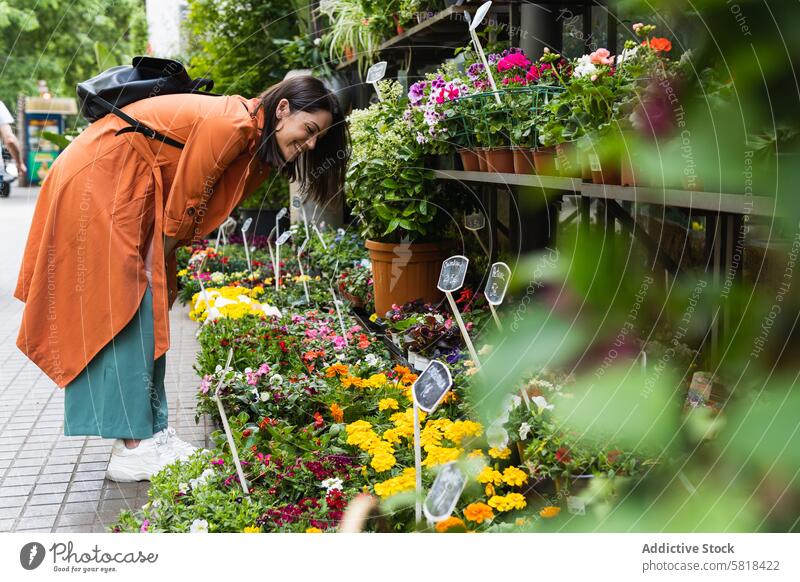 Fröhliche Frau wählt Blumen in einem Gartencenter aus Markt wählen Blütezeit pflücken Kunde Zentrum Großstadt Pflanze frisch organisch Gärtner Aroma wachsen