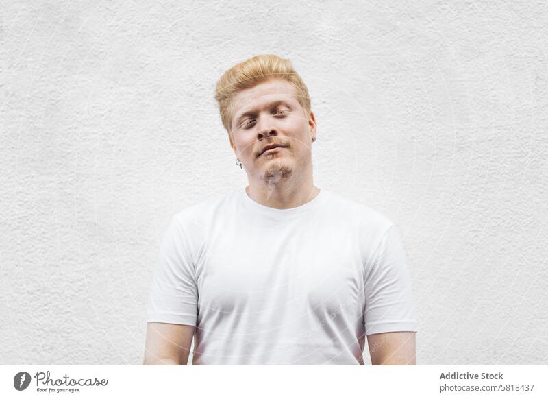 Monochrom: Porträt eines Albino-Latino-Mannes in weißer Kleidung vor einem weißen Hintergrund. männlich Typ blond Gesicht Person jung Behaarung Erwachsener