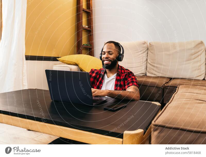 Schwarzer Mann arbeitet mit Laptop von zu Hause aus Telearbeit Computer Afroamerikaner heimwärts Internet freiberuflich abgelegen online benutzend schwarz