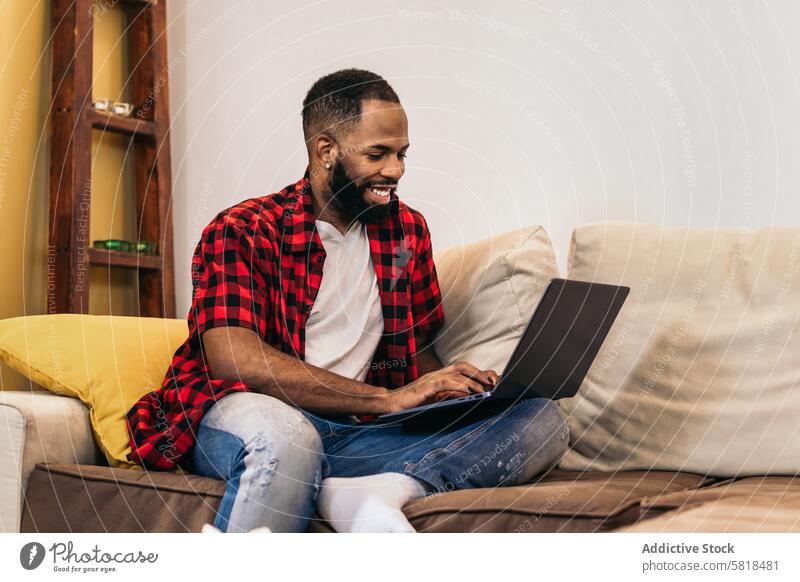 Schwarzer Mann arbeitet mit Laptop von zu Hause aus Telearbeit Computer Afroamerikaner heimwärts Internet freiberuflich abgelegen online benutzend schwarz