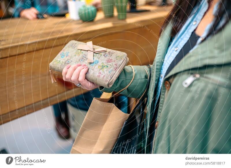 Unerkennbare Frau Kunde hält Brieftasche mit Schleife und ökologischen Einkaufen Papiertüten auf Speicher unkenntlich Klient Beteiligung Hand wiederverwerten