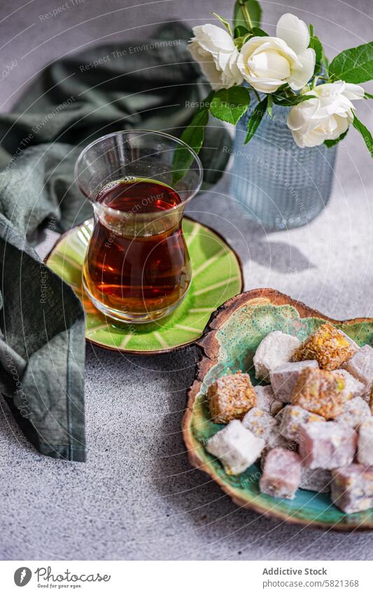 Türkische Köstlichkeiten und schwarzer Tee mit weißen Rosen Dekor türkische Freude Schwarzer Tee Glas weiße Rose Vase Keramikteller sortiert traditionell süß