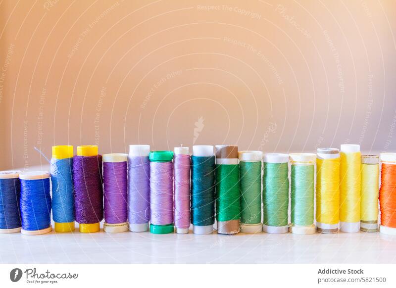 Lebendige Garnspulen auf neutralem Hintergrund aufgereiht Faser Spule Nähen Farbe Regenbogen Ordnung Textil Material Mode Design Werkstatt Handwerk Hobby