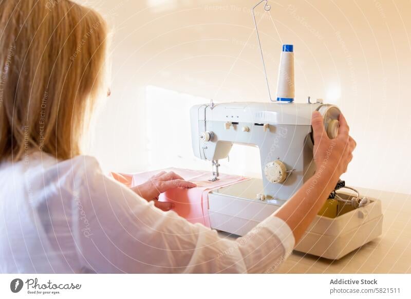 Näherin bei der Arbeit an der Nähmaschine in einer hellen Werkstatt Gewebe Näherei Textil Handwerkskunst Schneider Mode Design Faser Kleidungsstück Herstellung