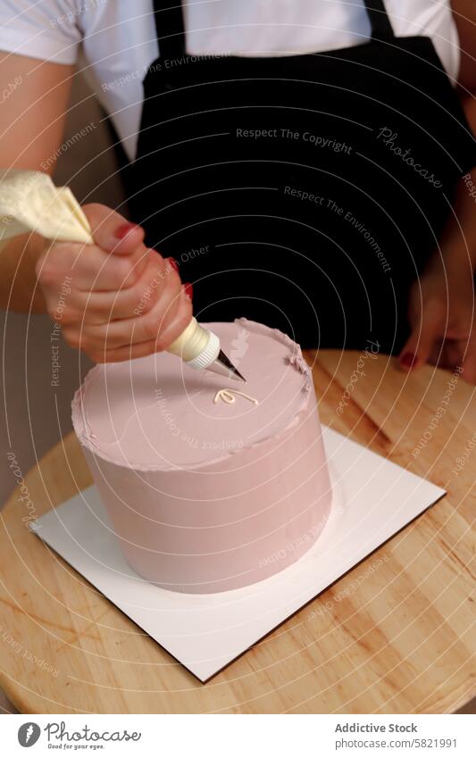 Eine Torte mit Präzision und Sorgfalt glasieren Person dekorierend Kuchen Zuckerguß Spritzbeutel rosa Detailaufnahme Zierde Dessert backen Konditorei Gebäck