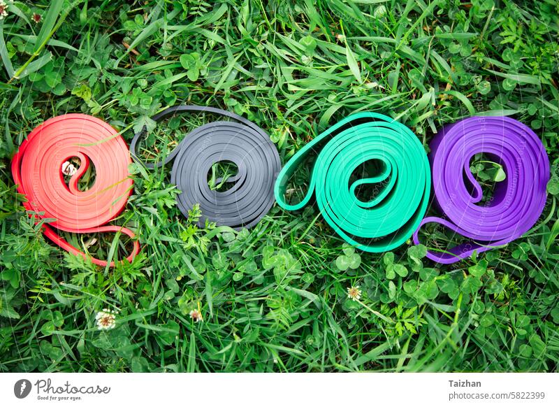 Satz von bunten elastischen Fitness-Bänder auf grünem Gras. Outdoor Workouts Konzept aktiv Erwachsener Athlet Band Gerät Übung Fett Ausrüstung Zahnfleisch