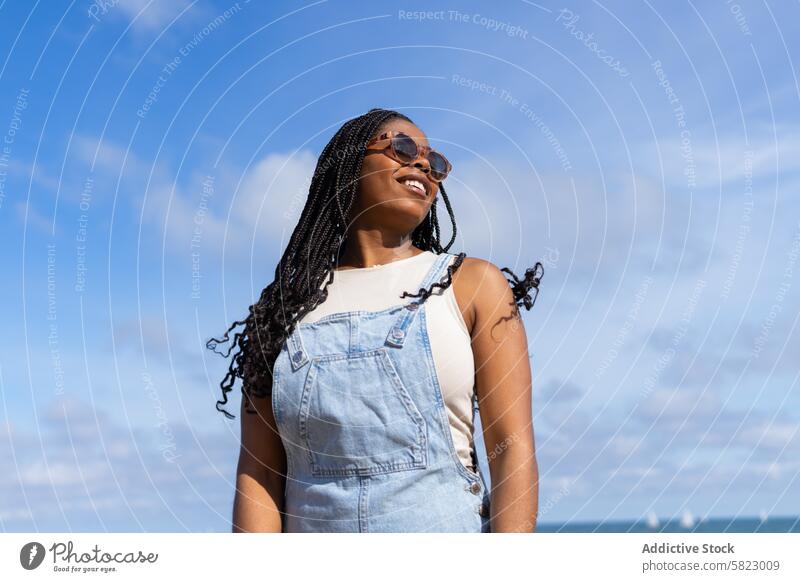 Lächelnde Frau genießt den Sommer in Barcelona Himmel Freude Jeansstoff Overall sorgenfrei Sprit Sonnenbrille Blauer Himmel Klarer Himmel Fröhlichkeit sonnig