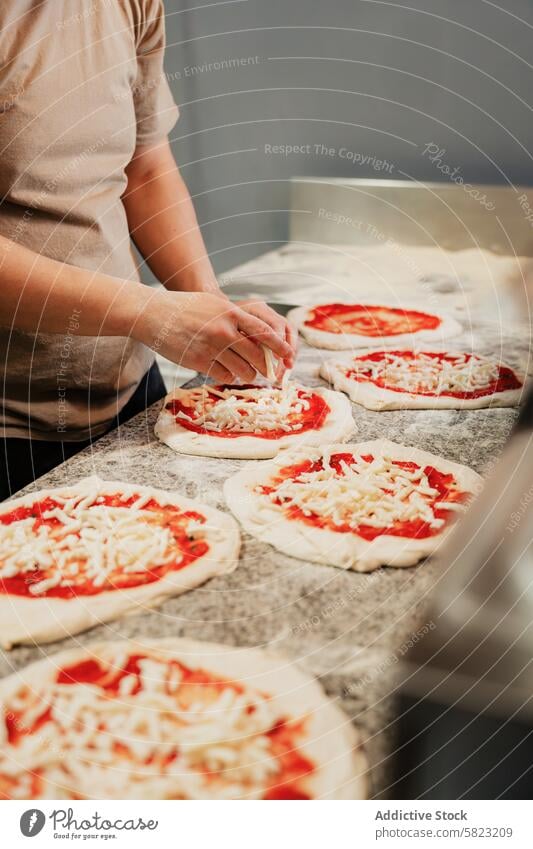 Handgemachte Pizzen in einer Pizzeria-Küche zubereiten Pizza Vorbereitung Küchenchef Teigwaren Saucen Käse handgefertigt Essen zubereiten anonym gesichtslos