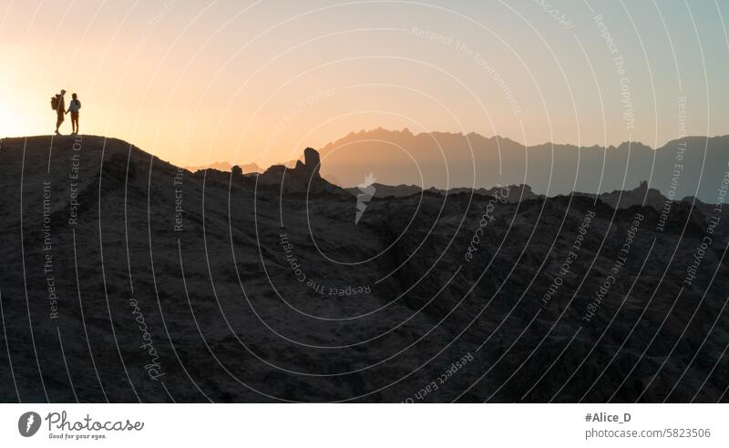 Paar Silhouette stehen auf hügeligen Landschaft im Gegenlicht von Sonnenuntergang Aktivität Abenteuer Afrika arabische wüste atmosphärisch Hintergrund hell